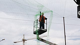 A municipal worker installs anti drone net to prevent Russian attacks on people and transport in Zaporizhzhia, Ukraine, Thursday, June 18, 2026.