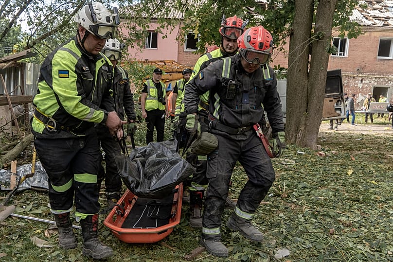 Des secouristes transportent un corps qu'ils ont dégagé des décombres d'un immeuble d'habitation après une frappe de missile russe à Kharkiv, en Ukraine, samedi 20 juin 2026. (AP Phot