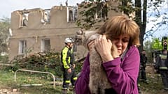 Une femme tient son chat dans ses bras après des opérations de recherche et de sauvetage menées dans l'immeuble résidentiel suite à l'attaque russe à Kharkiv, 20.06.2026