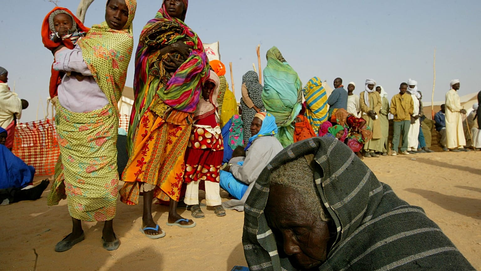 لاجئ سوداني يرقد على الأرض يوم الاثنين 26 يناير/كانون الثاني 2004 بينما يصطف لاجئون آخرون لتلقي الرعاية الطبية في مخيم أطباء بلا حدود في تين على الجانب التشادي من الحدود السود