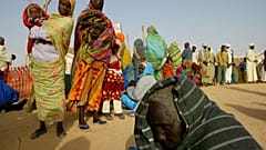 لاجئ سوداني يرقد على الأرض يوم الاثنين 26 يناير/كانون الثاني 2004 بينما يصطف لاجئون آخرون لتلقي الرعاية الطبية في مخيم أطباء بلا حدود في تين على الجانب التشادي من الحدود السود