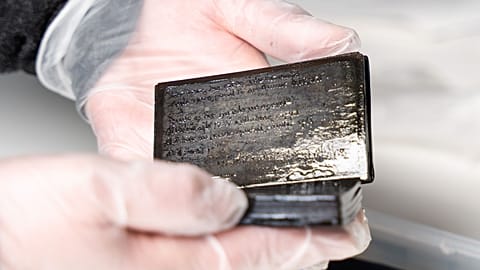 Conservator Susanne Bretzel holds the small wax booklet up to the camera.