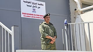 Un soldato libico di guardia durante una manifestazione davanti alla sede dell’UNHCR a Tripoli, in Libia, in cui si chiedeva la chiusura dell'ufficio (4 giugno 2026) 