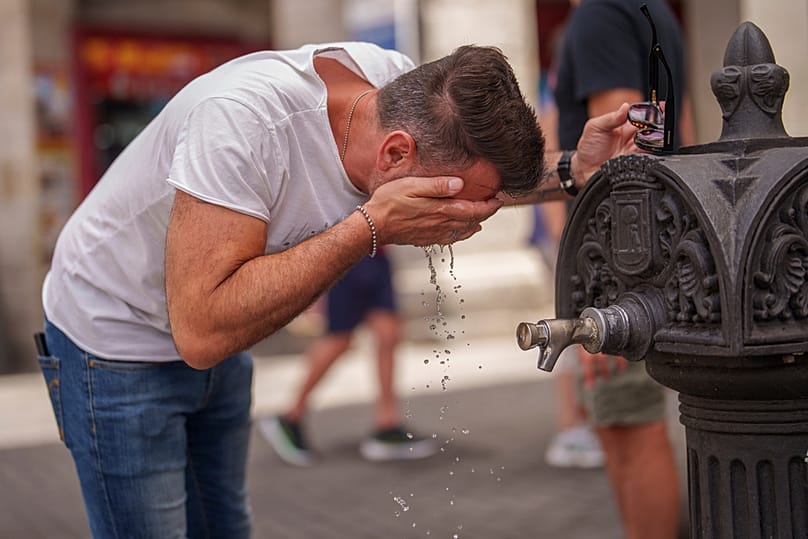 FILE - A man cools off in a fountain during a hot and sunny day of summer in Madrid, Spain, July 19, 2023.