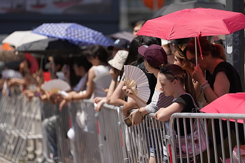 People wait in the heat the arrival of guests of the Prada's Spring/Summer 2027 men's collection presented in Milan, Italy, Sunday, June 21, 2026.