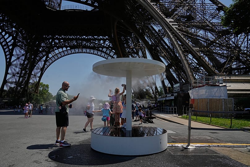People cool off in a water spray at the Eiffel Tower in Paris, Sunday, June 21, 2026