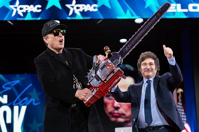 Elon Musk muestra la motosierra que recibió del presidente argentino Javier Milei a su llegada para hablar en la CPAC, el 20 de febrero de 2025, en Oxon Hill, Maryland.