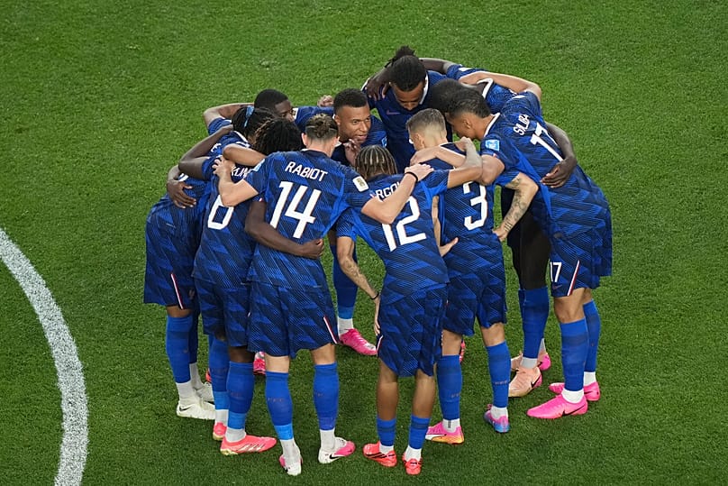 Kylian Mbappé s'entretient avec ses coéquipiers après un retard dû aux conditions météorologiques lors du match de football France-Irak