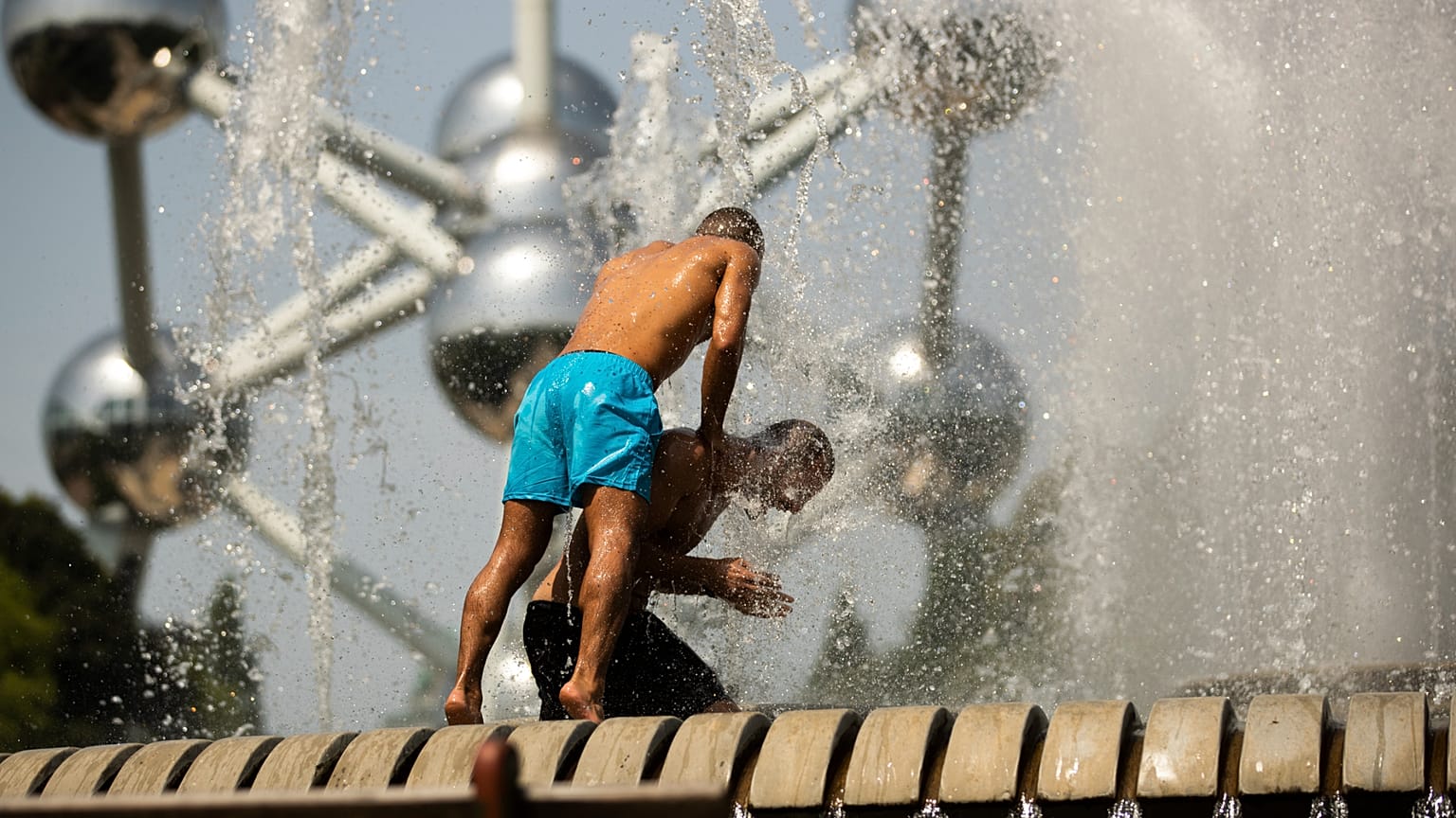 Two men cool off in a public fountain near the Atomium during a summer hot day in Brussels