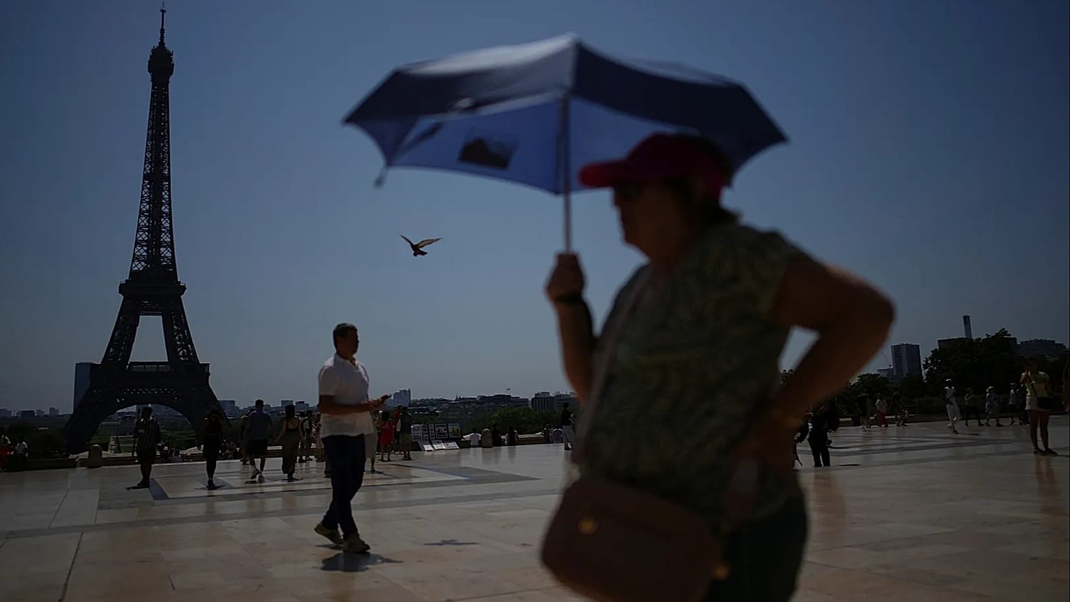 Ludzie spacerują po placu Trocadéro w pobliżu wieży Eiffla podczas fali upałów w Paryżu