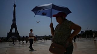 Des passants se promènent sur la place du Trocadéro, près de la tour Eiffel, en pleine vague de chaleur à Paris