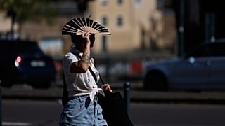 A woman shields herself from the sun with a fan in Rennes, western France, Monday, June 22, 2026. 