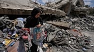 امرأة تجمع ألعاب أطفالها وبعض مقتنياتهم من منزلها المدمّر بعد وقف إطلاق النار، في 22 يونيو 2026.