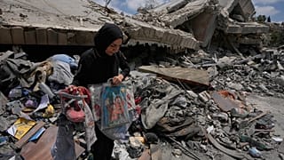 امرأة تجمع ألعاب أطفالها وبعض مقتنياتهم من منزلها المدمّر بعد وقف إطلاق النار، في 22 يونيو 2026.
