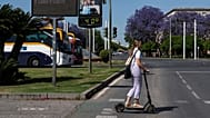 Ein Mädchen fährt in Spanien ohne Helm mit einem E-Scooter.