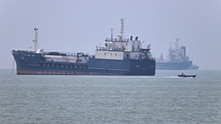 Kleines Motorboot passiert ankernde Schiffe in der Straße von Hormus