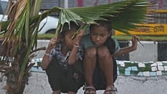 Mädchen suchen unter Palmblättern Schutz vor einem Monsunregen in Mumbai, Indien, am Sonntag, 21. Juni 2026.