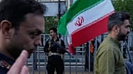 FILE: A security personnel stands guard as a man carries an Iranian flag during a state-organised rally in Tehran, 29 April 2026