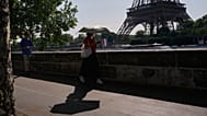 A woman shields herself from the sun as she walks near the Eiffel Tower in Paris 