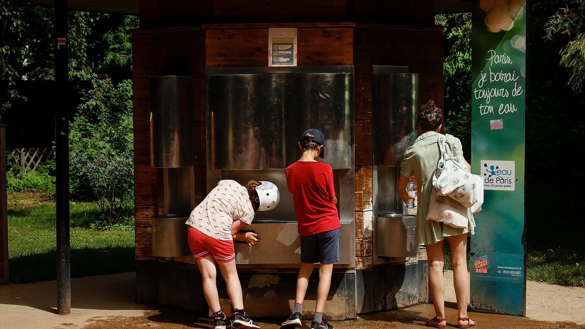 Una donna e alcuni bambini vanno a prendere l'acqua alla fontana in un parco, sabato 18 giugno 2022, a Parigi.