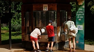 Eine Frau und mehrere Kinder holen am Samstag, den 18. Juni 2022, Wasser an einem Brunnen in einem Park in Paris.