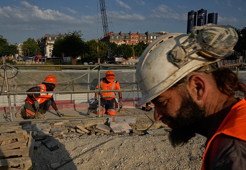 Construction workers work at a massive construction site as temperatures are expected to reach record highs in Paris, Wednesday, June 24, 2026. 
