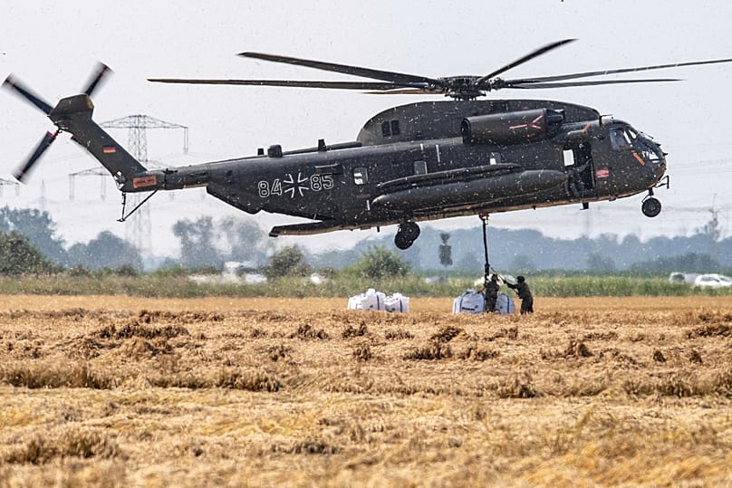 Flutkatastrophe 2021: Ein Transporthubschrauber der Bundeswehr nimmt große Ballastsäcke auf, um sie am Ufer abzustauen.