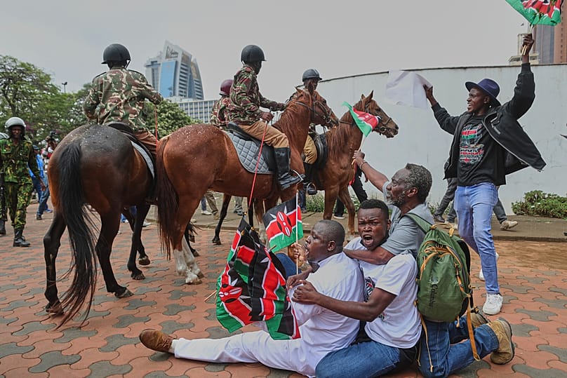 Protesters sing and wave Kenyan flags near Parliament during a demonstration marking two years since the 2024 anti-government protests in Nairobi, Kenya, June 25, 2026