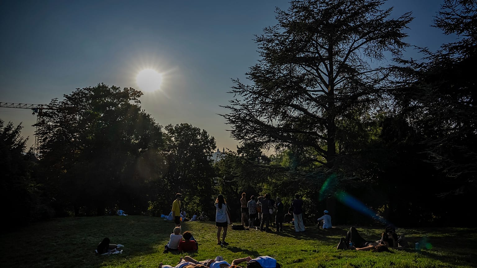 People rest in the Parc des Buttes Chaumont in Paris, Saturday, Aug. 16, 2025