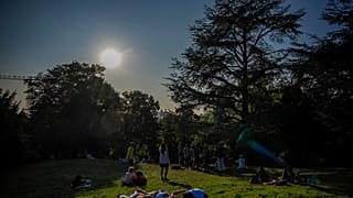 People rest in the Parc des Buttes Chaumont in Paris, Saturday, Aug. 16, 2025
