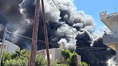 Σύννεφο καπνού υψώνεται πάνω από σπίτια στην πόλη του Ηρακλείου εξαιτίας της πυρκαγιάς που ξέσπασε σε αποθήκη ξυλείας