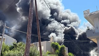 Σύννεφο καπνού υψώνεται πάνω από σπίτια στην πόλη του Ηρακλείου εξαιτίας της πυρκαγιάς που ξέσπασε σε αποθήκη ξυλείας