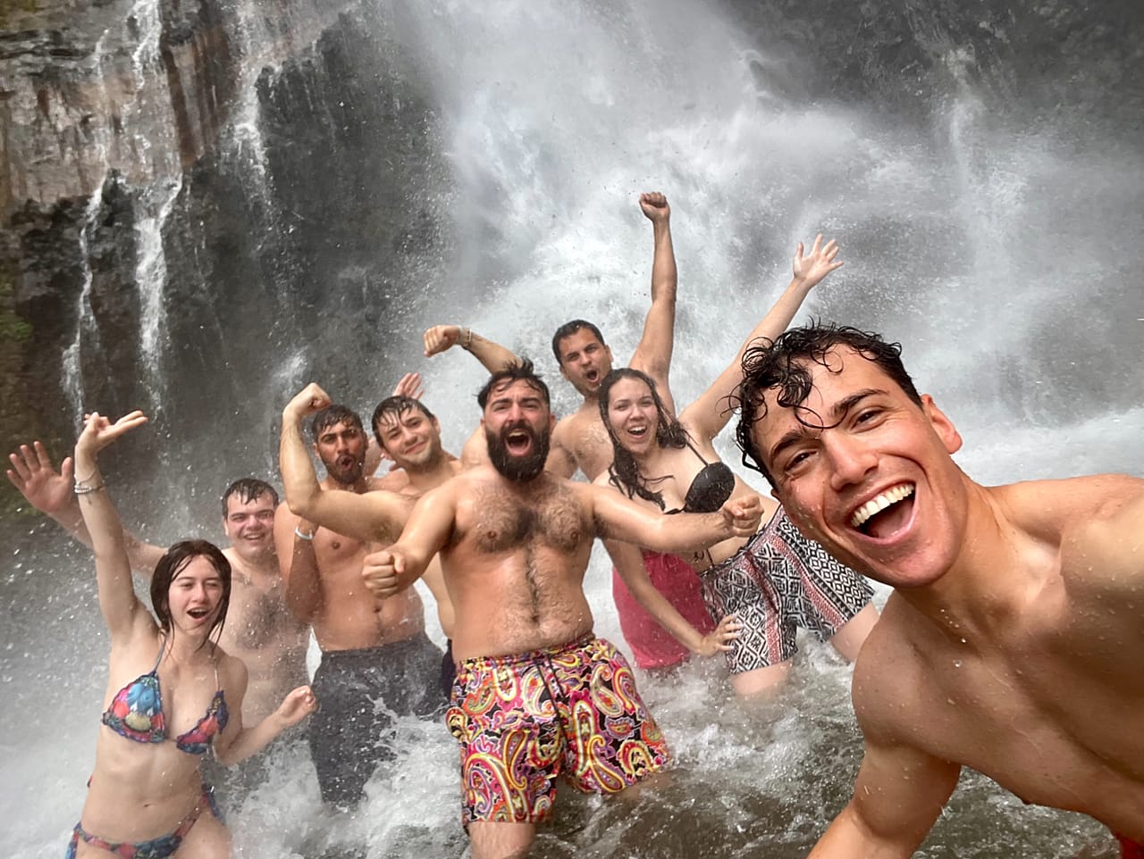 Endonezya'da bir şelalenin altında grup selfie çeken WeRoad gezginleri
