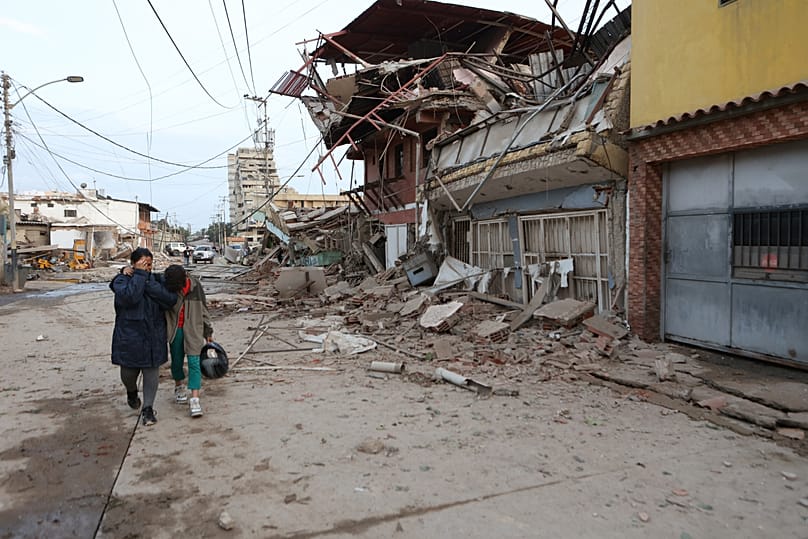 Residentes caminan junto a edificios dañados tras un terremoto en La Guaira, Venezuela, el jueves 25 de junio de 2026. (AP Photo/Pedro Mattey)