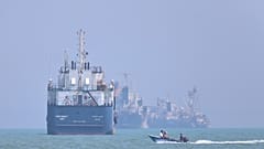 ARCHIV: Ein kleines Motorboot fährt an vor Anker liegenden Schiffen in der Straße von Hormus vor Bandar Abbas vorbei, am elften Juni 2026.