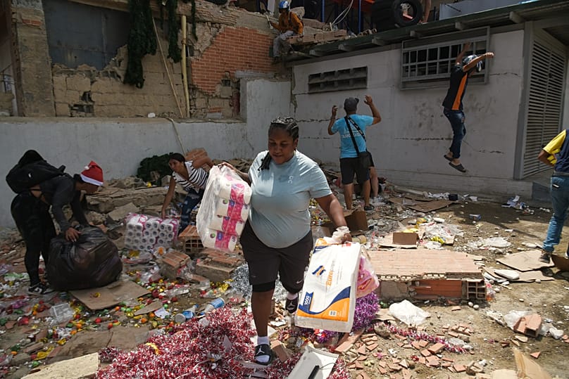 Un día después de que terremotos y réplicas sacudieran Catia La Mar, Venezuela, el jueves 25 de junio de 2026, varias personas retiran mercancías de tiendas dañadas. 