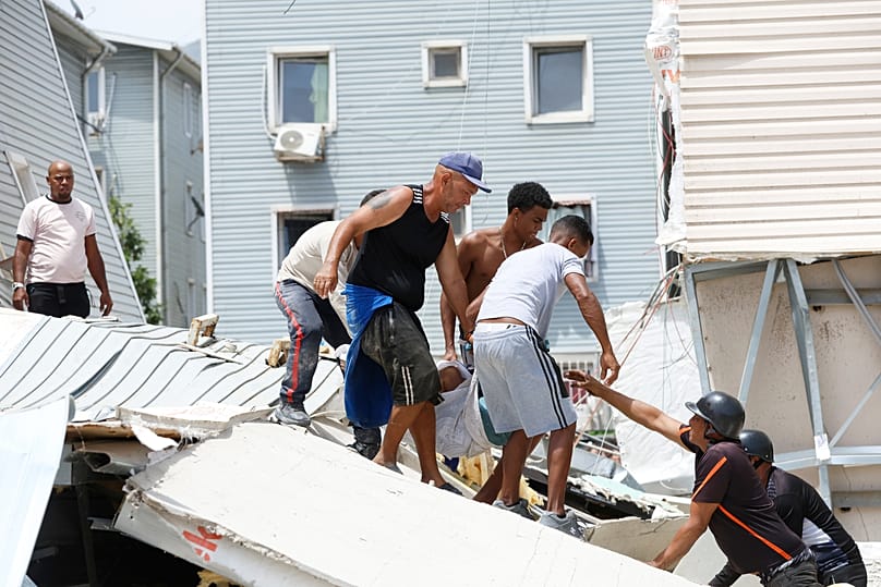 Vecinos transportan los cuerpos de dos de los hijos de Gabriela Rojas, quienes fallecieron en su hogar durante el terremoto que azotó La Guaira, Venezuela