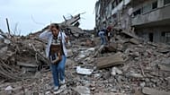 Residents walk among the rubble of building damaged in earthquakes the previous day in Catia La Mar, Venezuela, Thursday, June 25, 2026
