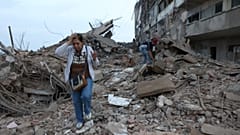 Venezuela'nın Catia La Mar kentinde, 25 Haziran 2026 Perşembe günü, önceki günkü depremlerde hasar gören bir binanın enkazı arasında sakinler yürüyor.
