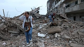 Residents walk among the rubble of building damaged in earthquakes the previous day in Catia La Mar, Venezuela, Thursday, June 25, 2026