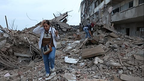 Residents walk among the rubble of building damaged in earthquakes the previous day in Catia La Mar, Venezuela, Thursday, June 25, 2026