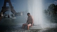 شخص يبرد نفسه عند نافورة تروكاديرو بالقرب من برج إيفل أثناء موجة الحر في باريس، الأربعاء 24 يونيو 2026. (AP Photo/كريستوف إينا)