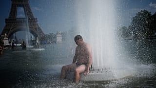 شخص يبرد نفسه عند نافورة تروكاديرو بالقرب من برج إيفل أثناء موجة الحر في باريس، الأربعاء 24 يونيو 2026. (AP Photo/كريستوف إينا)