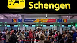 Passengers arriving at the Henri Coanda International Airport pass under a Schengen Information sign, in Otopeni, near Bucharest, Romania.