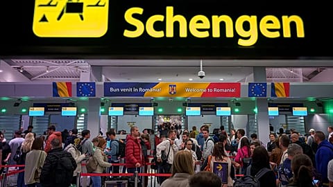 Des passagers arrivant à l'aéroport international Henri-Coandă passent sous un panneau d'information Schengen, à Otopeni, près de Bucarest, en Roumanie.