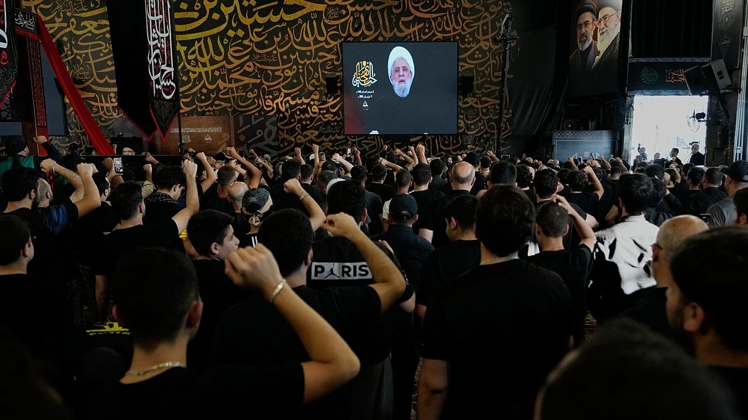 أنصار حزب الله يرفعون قبضاتهم وهم يستمعون إلى خطاب زعيم حزب الله الشيخ نعيم قاسم خلال خطبة بمناسبة اليوم الأول من عاشوراء