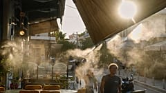 Pedestrians walk next to a mist machine in Thisio district of Athens during a heatwave, July 2025.