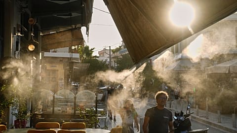 Járókelők mennek el egy párásító berendezés mellett Athén Thisszío negyedében egy hőhullám idején, 2025 júliusában.