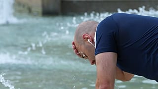 Un homme se rafraîchit dans une fontaine au château Sforza, dans le centre de Milan, en Italie, le jeudi 25 juin 2026.