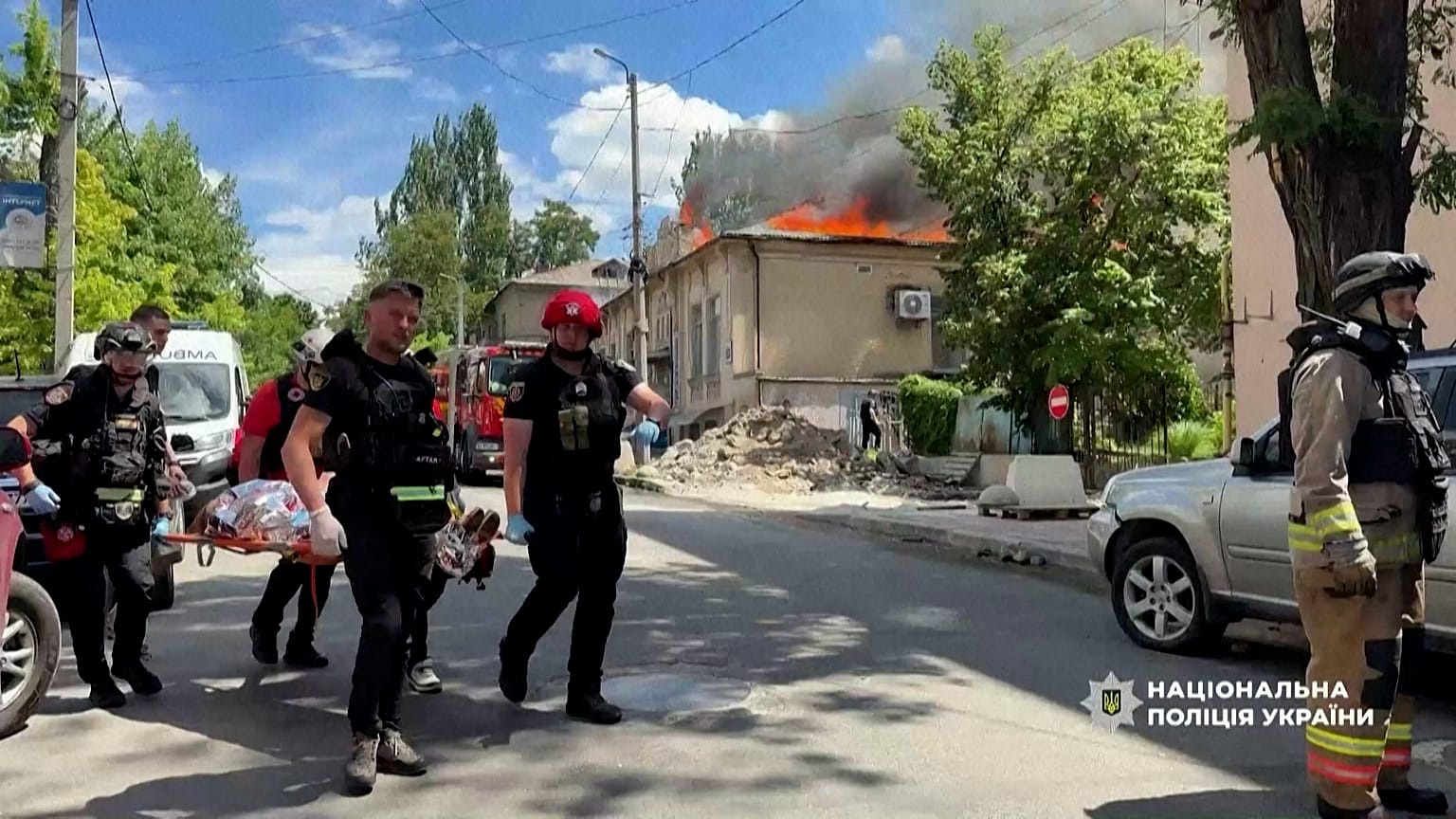 Los servicios de emergencia evacuan a una mujer herida de un edificio en llamas